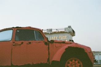 an old red truck parked in a parking lot