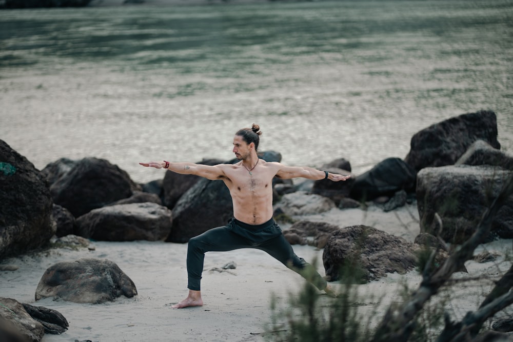 un uomo che fa una posizione yoga sulla spiaggia