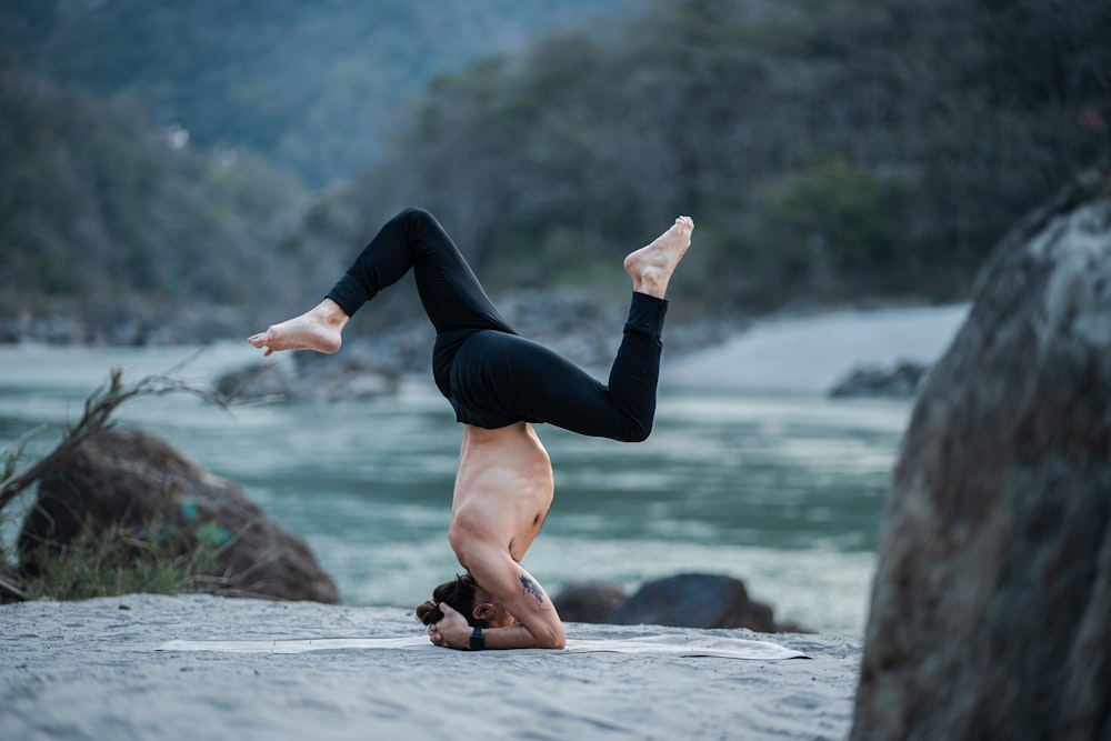 a woman doing a handstand on a beach