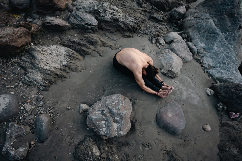 a man laying on top of a rocky beach
