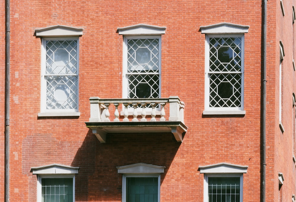 a red brick building with two windows and a balcony