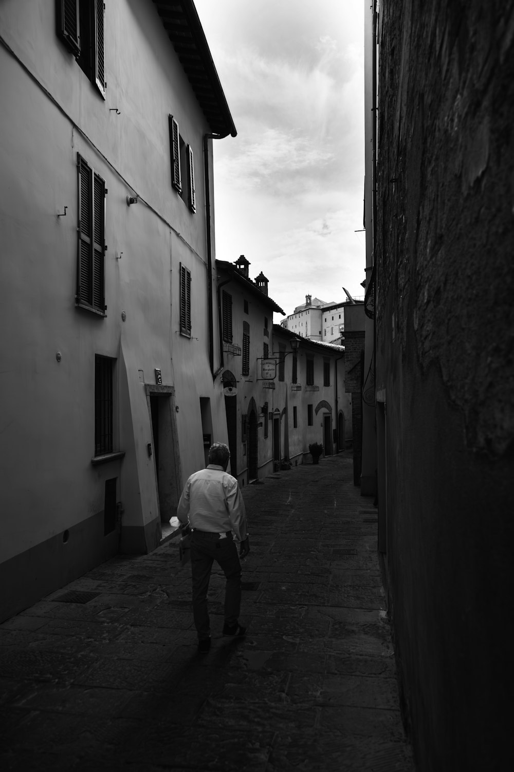 a black and white photo of a man walking down a street