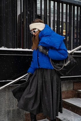 a woman wearing a blue jacket and black skirt