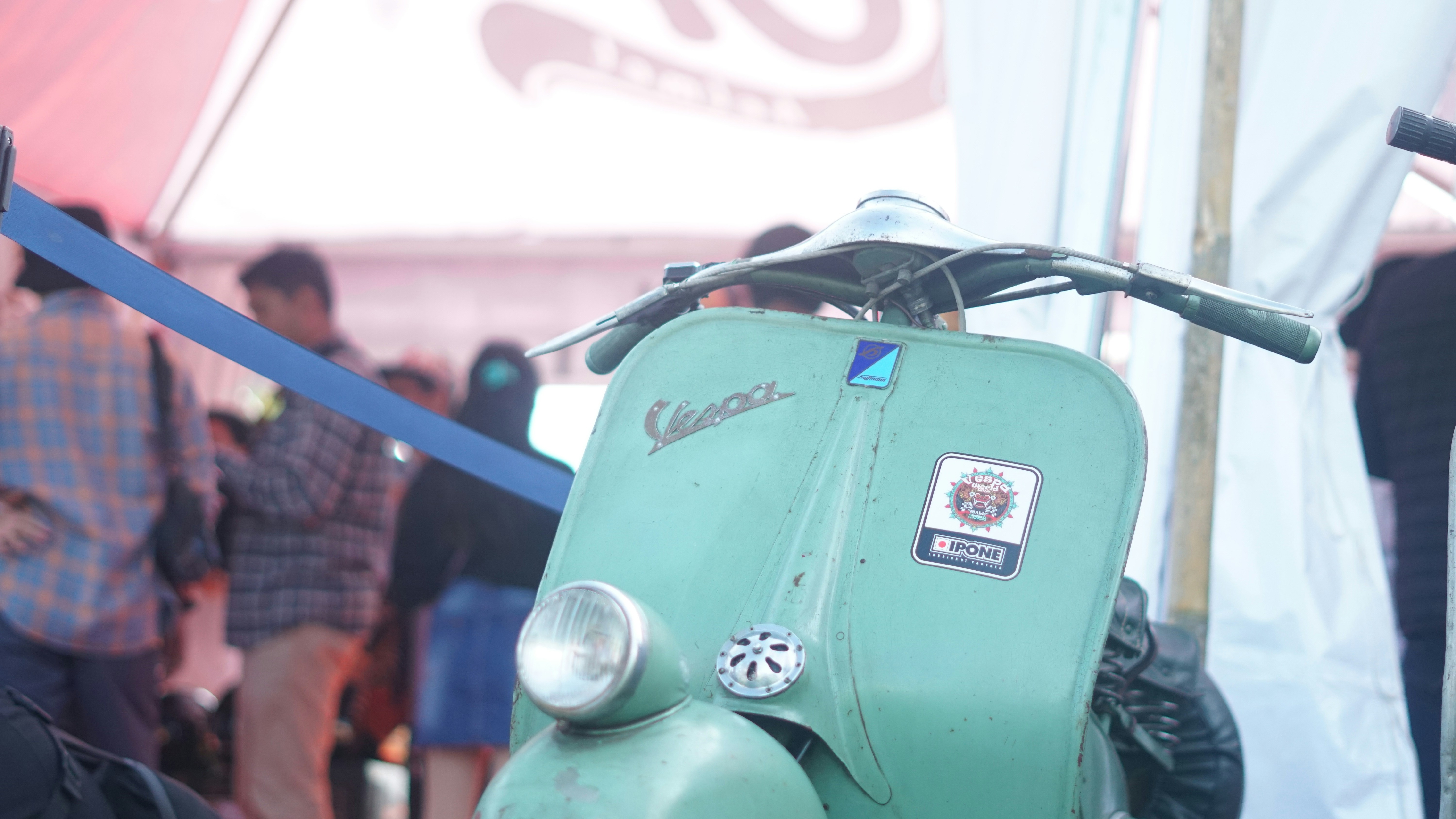 a green scooter parked next to a crowd of people