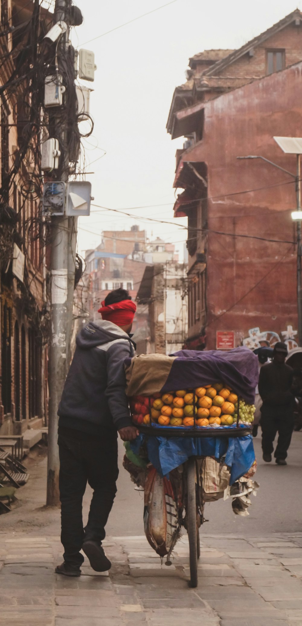 a man pushing a cart full of oranges down a street