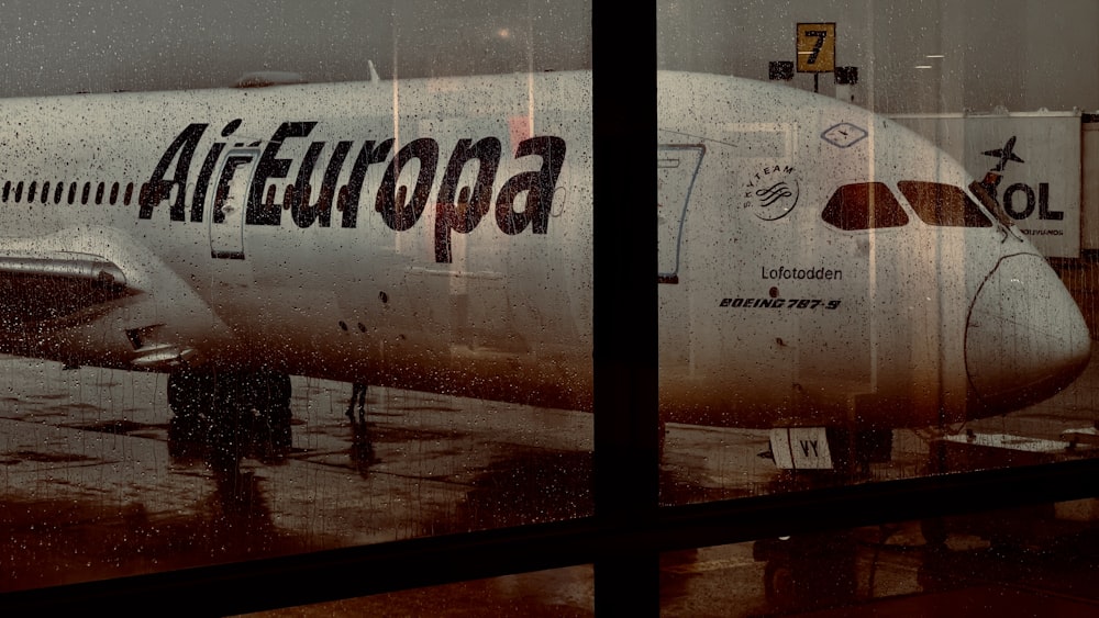 un grande aereo di linea seduto in cima alla pista di un aeroporto