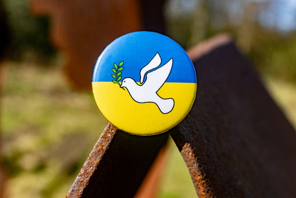 a blue and yellow pin with a white dove on it