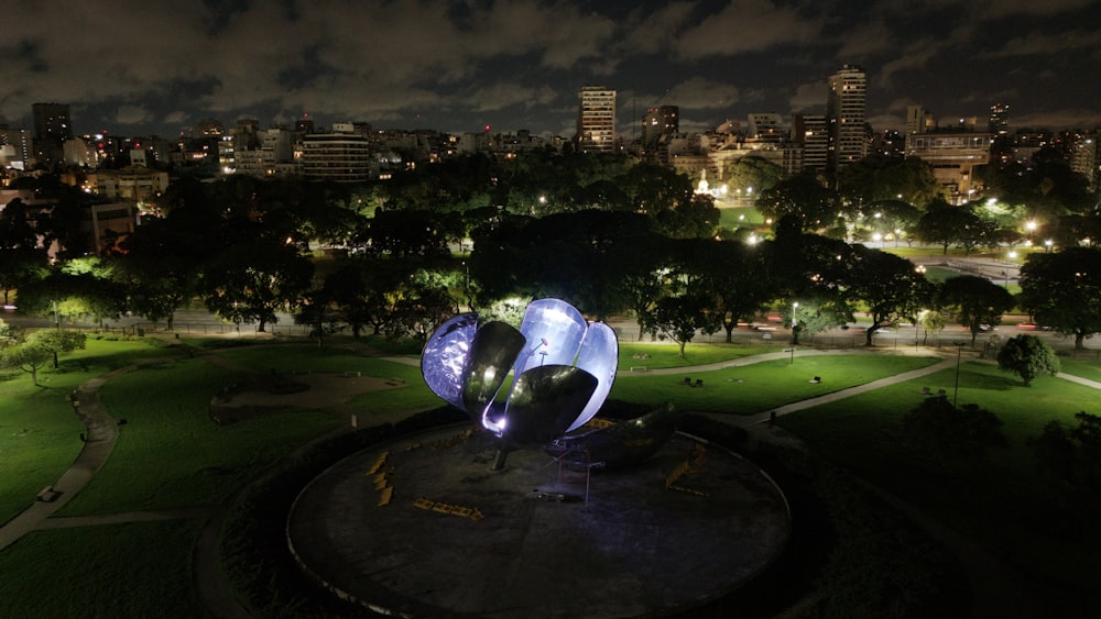 a night view of a park with a sculpture in the foreground