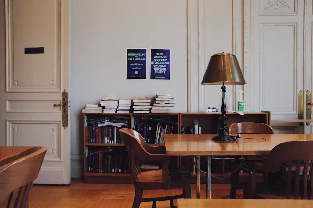 a room with a table, chairs, bookshelf and a lamp