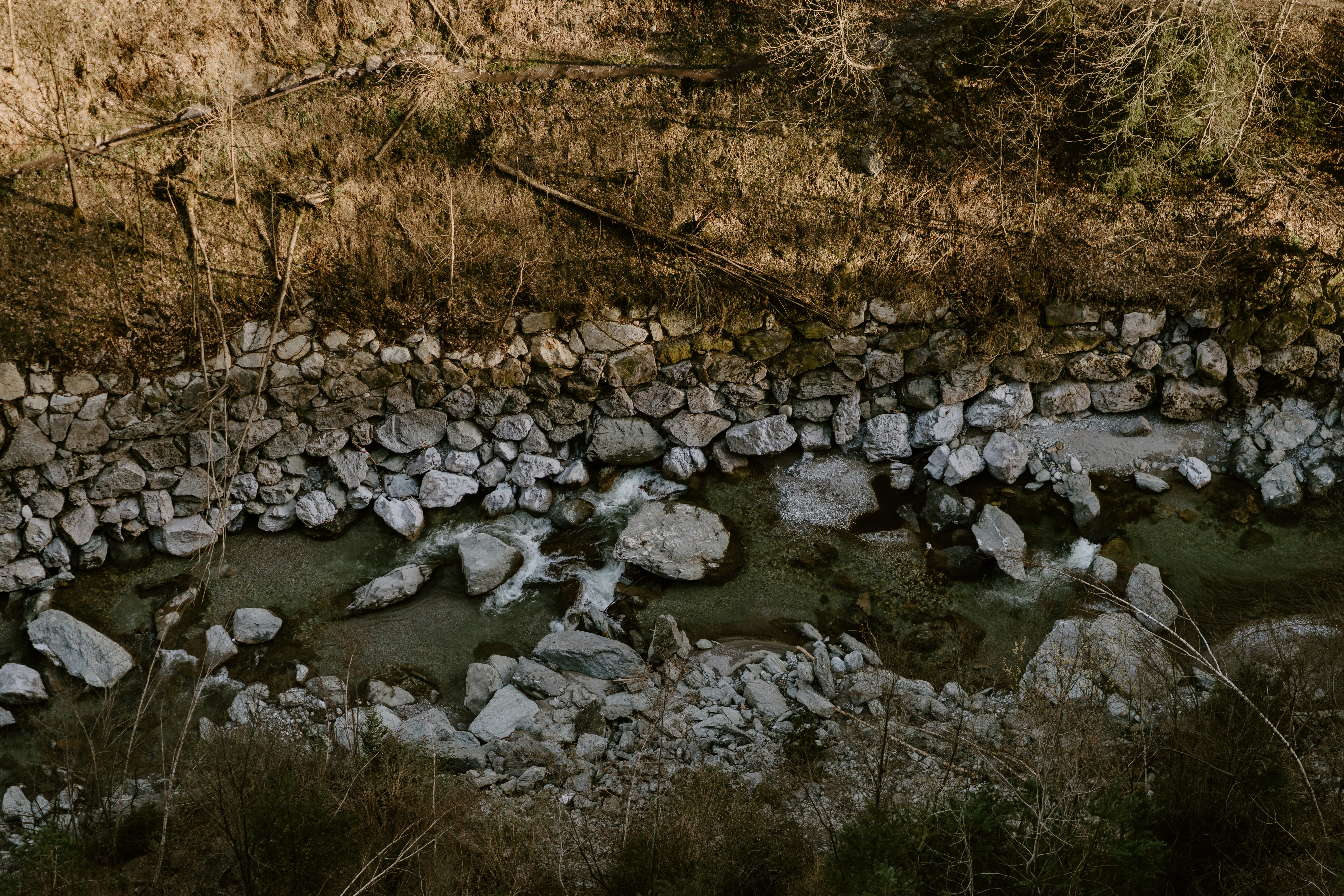 a river running through a dry grass covered hillside