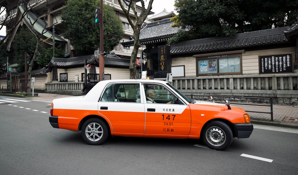 an orange and white taxi cab driving down a street