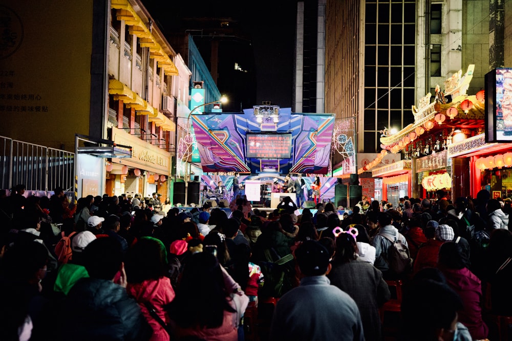 a crowd of people walking down a street at night