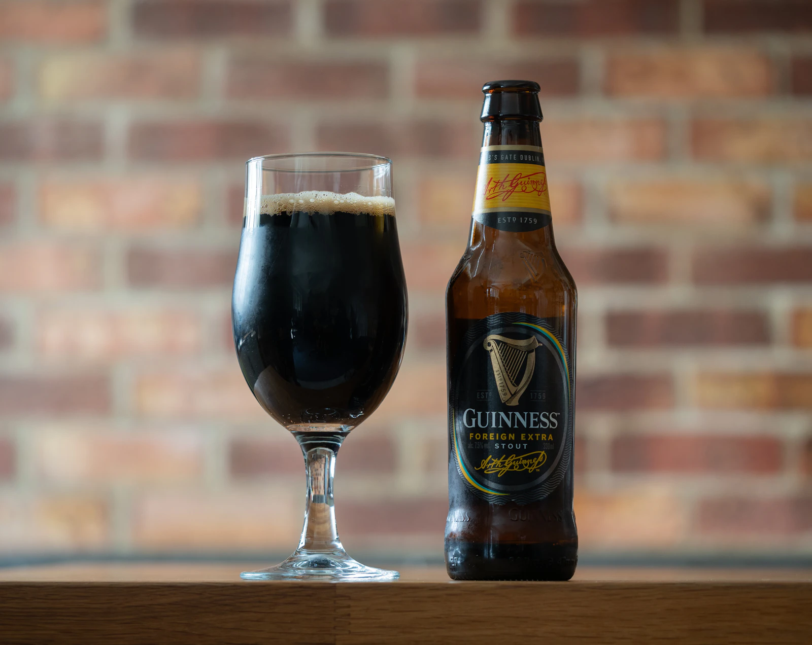 A close-up of a dark stout pour beside a glass.