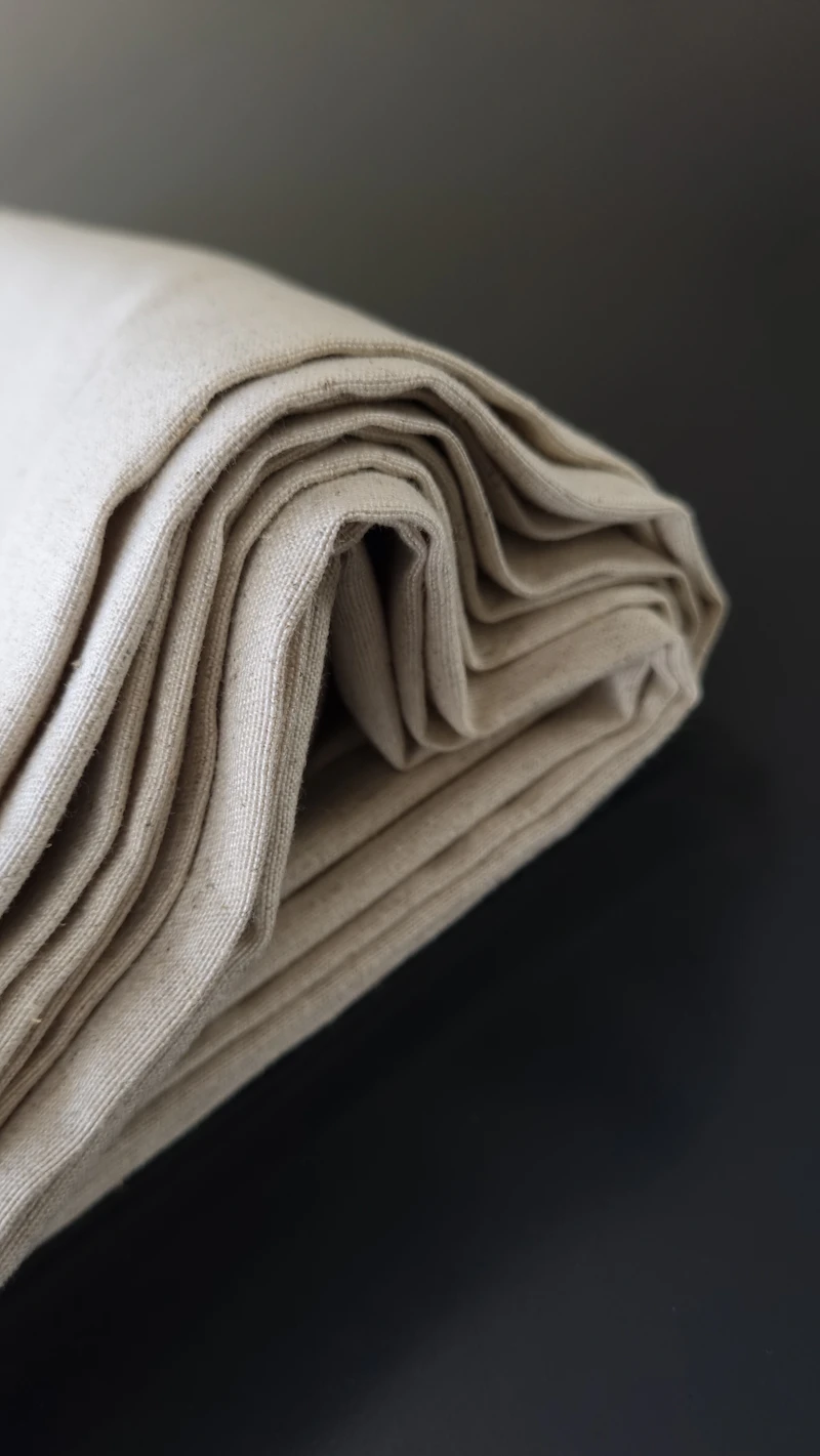 A folded natural linen tablecloth on a dark table