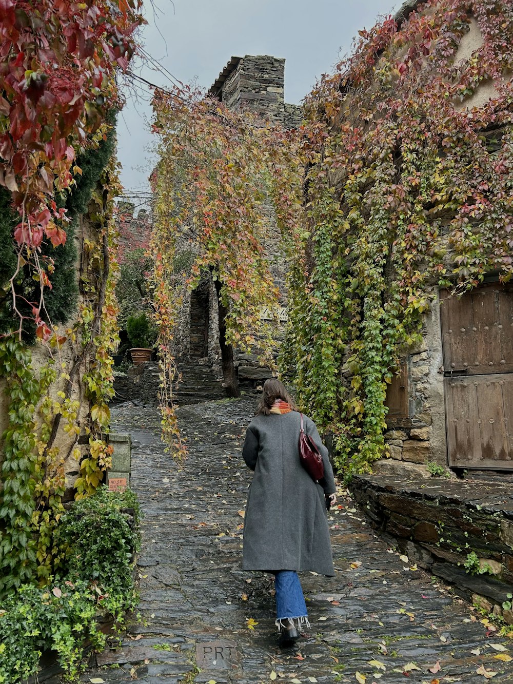 a woman is walking down a cobblestone street