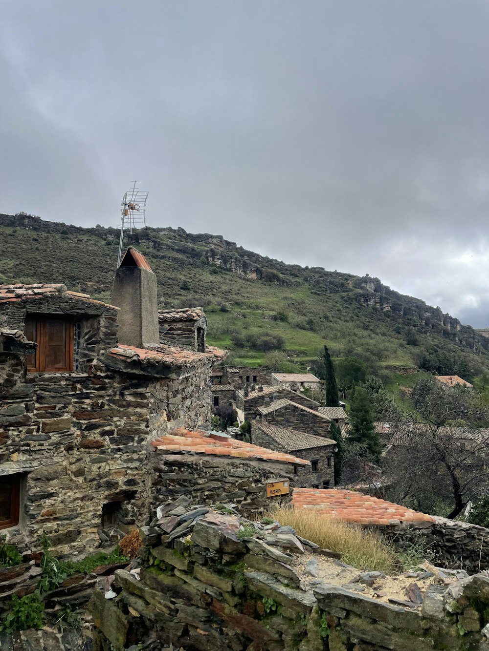 a stone building with a steep hill in the background