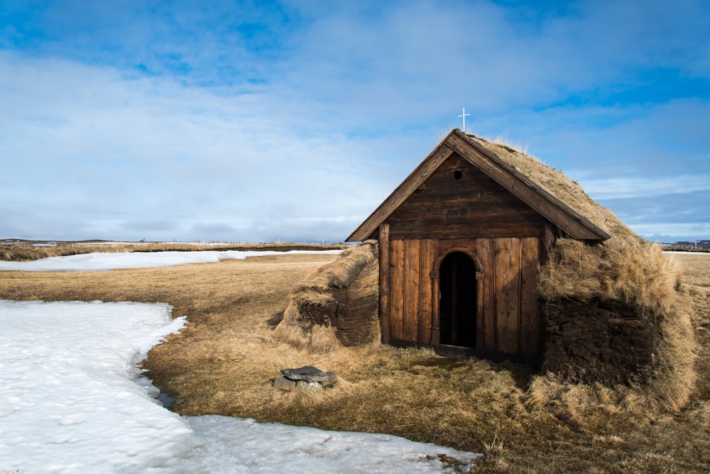 a small hut in a field with snow on the ground