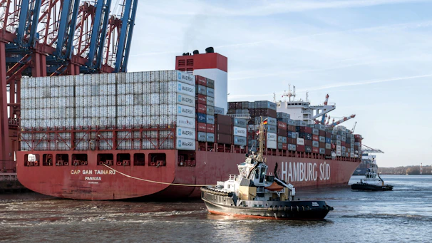 a tug boat pulling a large container ship