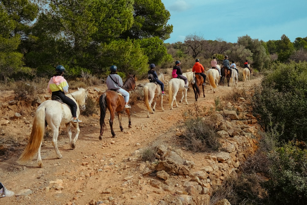 a group of people riding horses down a dirt road
