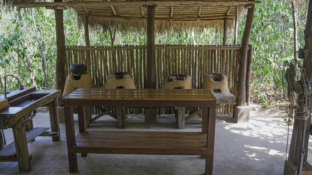 a wooden table sitting under a thatched roof