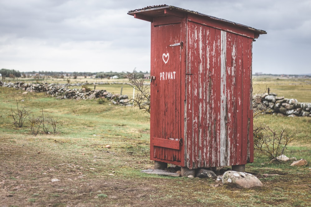 a red outhouse with a heart painted on it