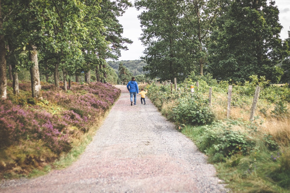 a couple of people walking down a dirt road