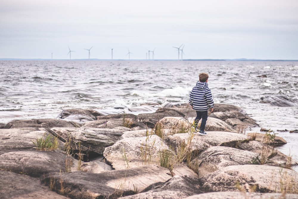 a person standing on rocks near the ocean