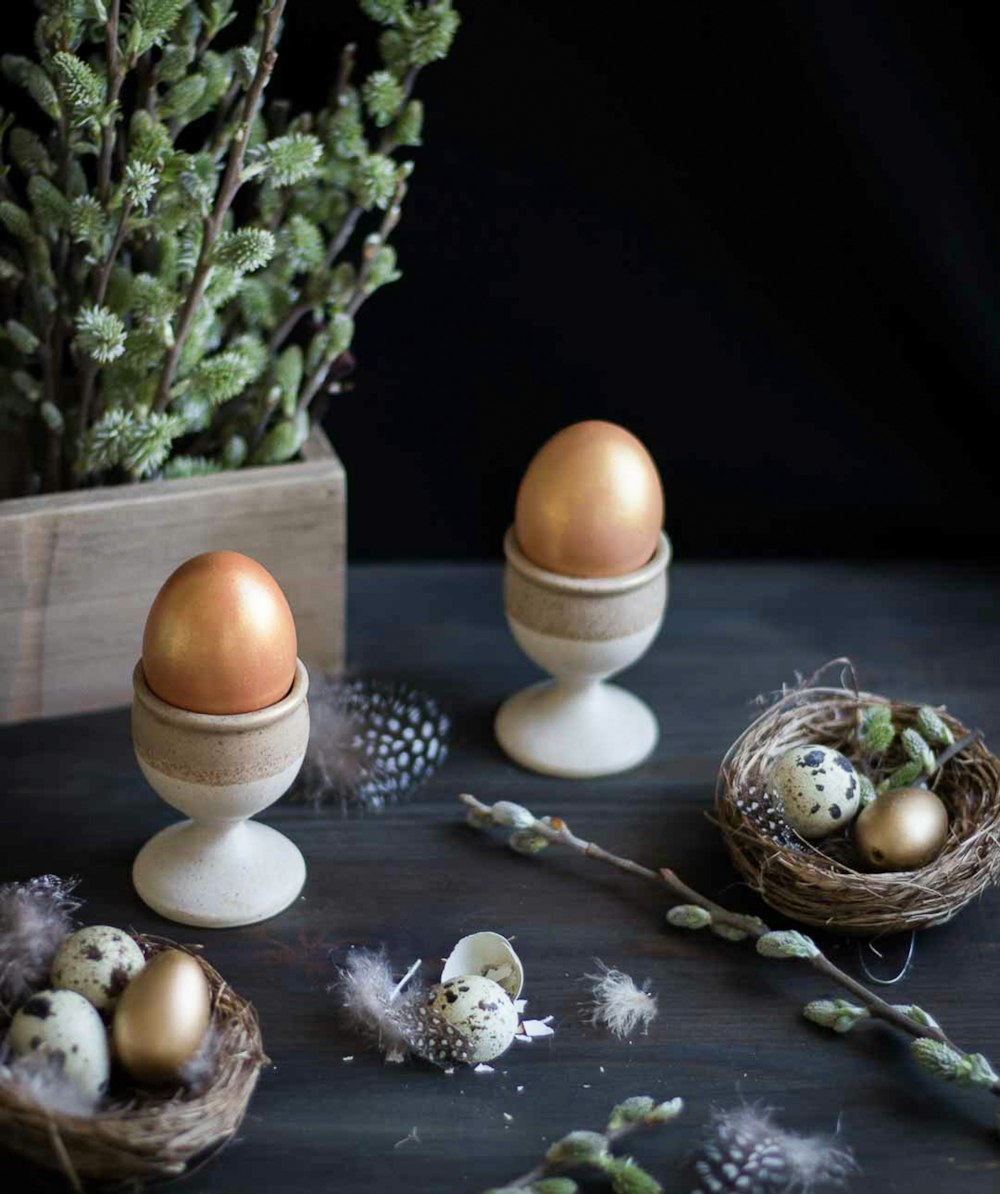 a table topped with two eggs and a nest