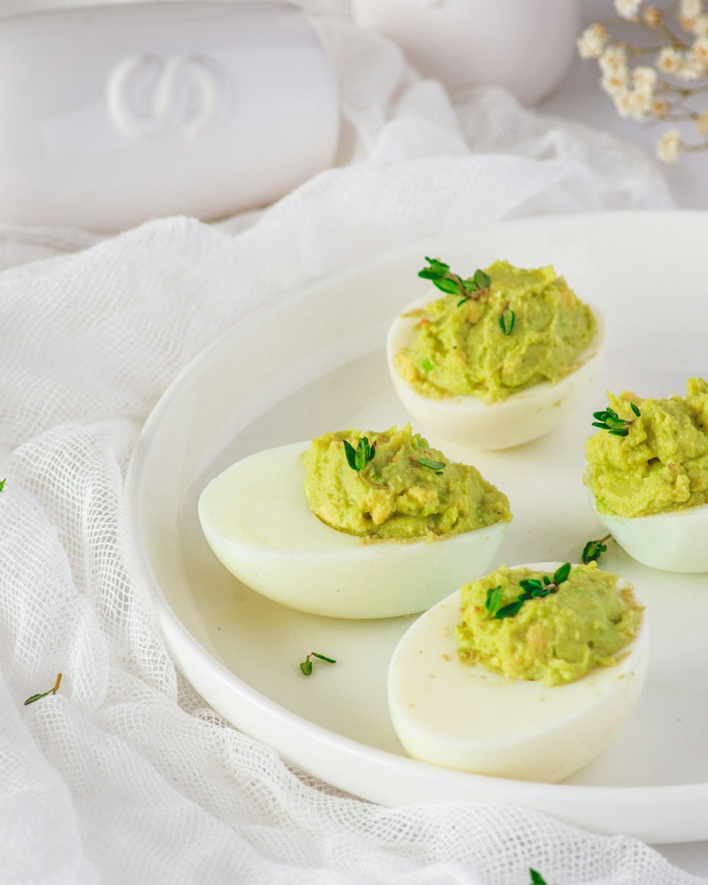 deviled eggs with guacamole on a white plate