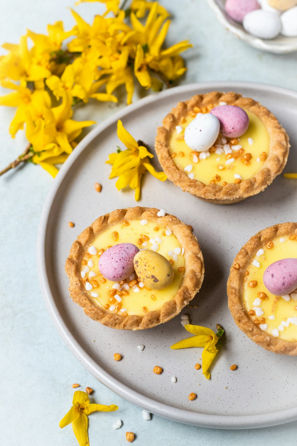 three small desserts on a plate with yellow flowers