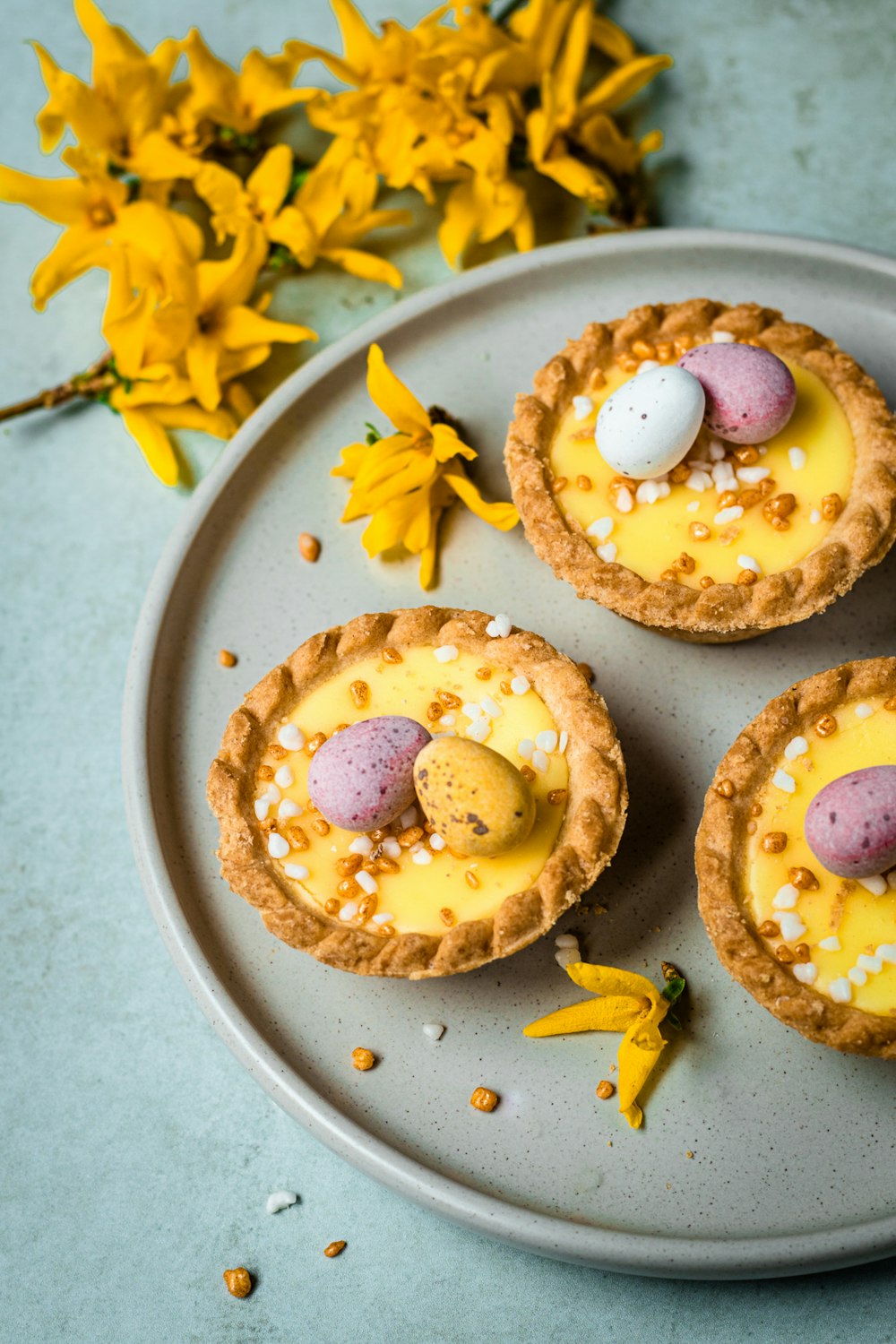 three small desserts on a plate with yellow flowers
