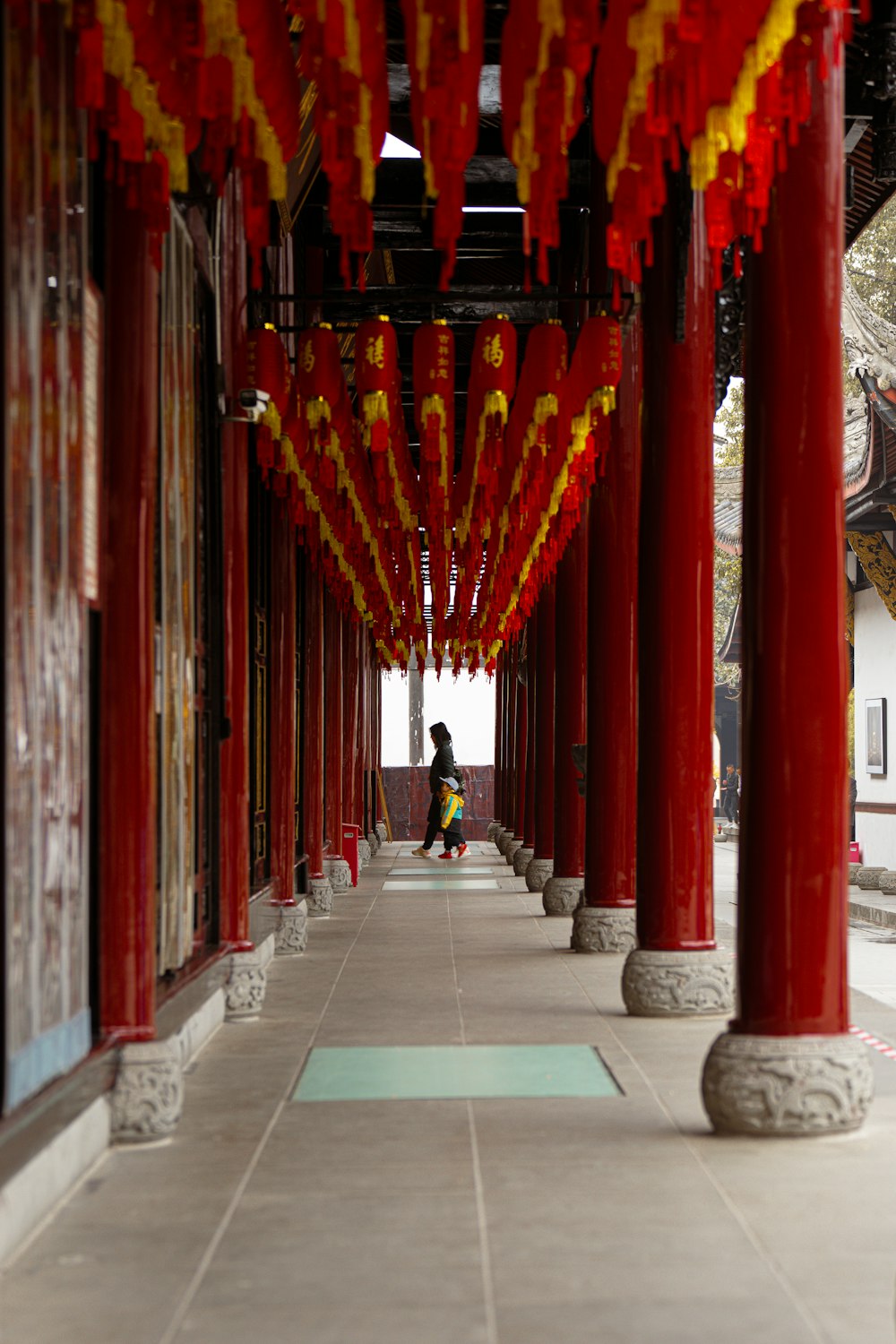 a woman walking down a long hallway covered in red and yellow decorations