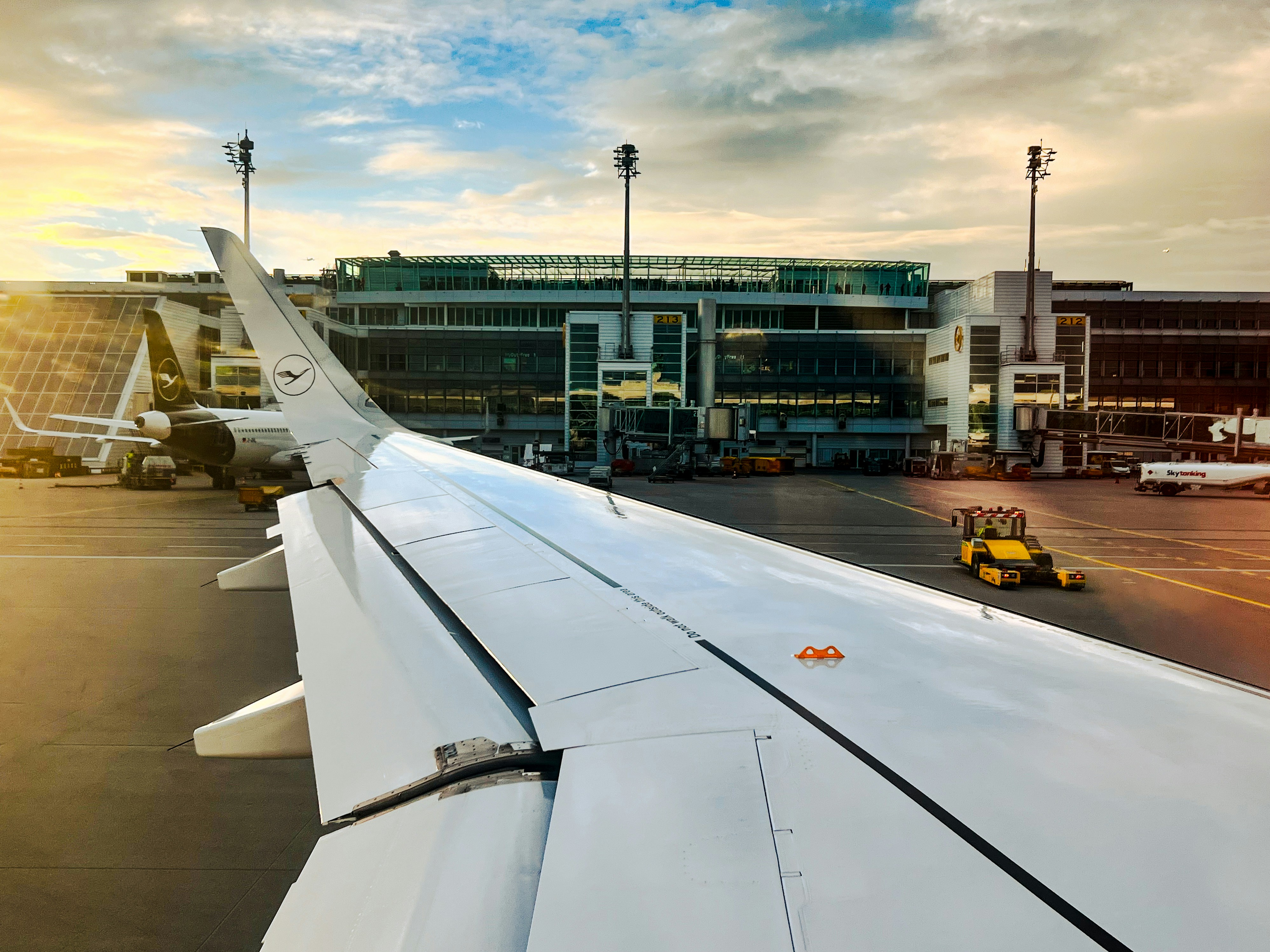 the wing of an airplane with a building in the background, Lufthansa A320 ready for taxi at Munich Airport