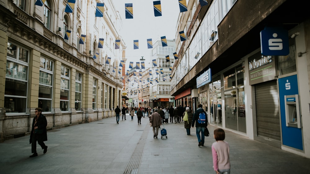 a group of people walking down a street next to tall buildings