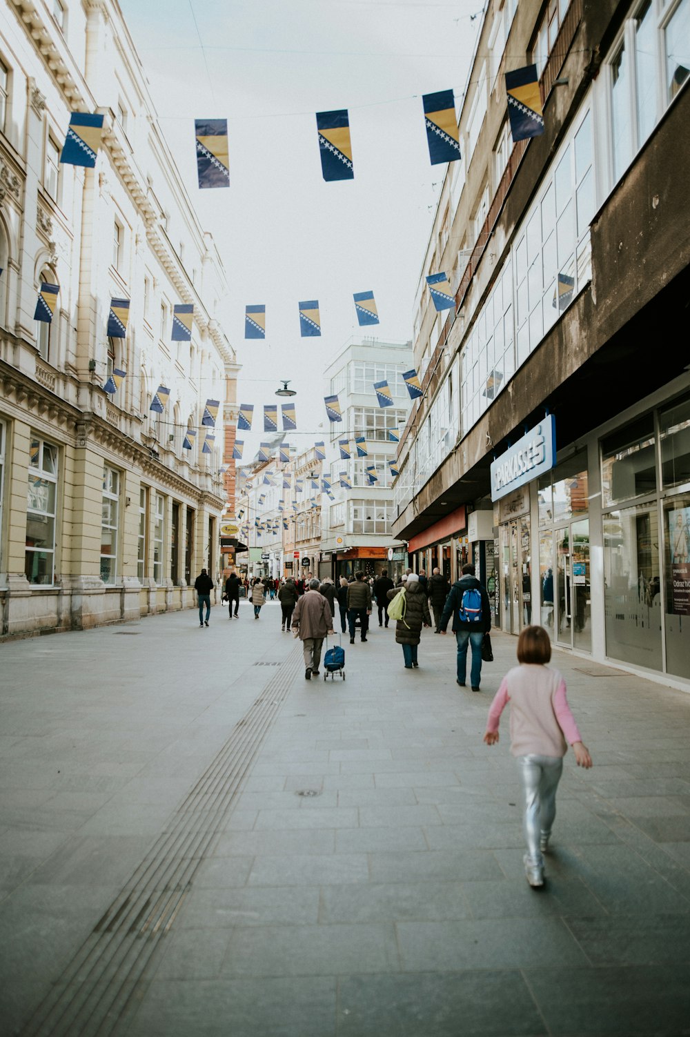 a group of people walking down a street next to tall buildings