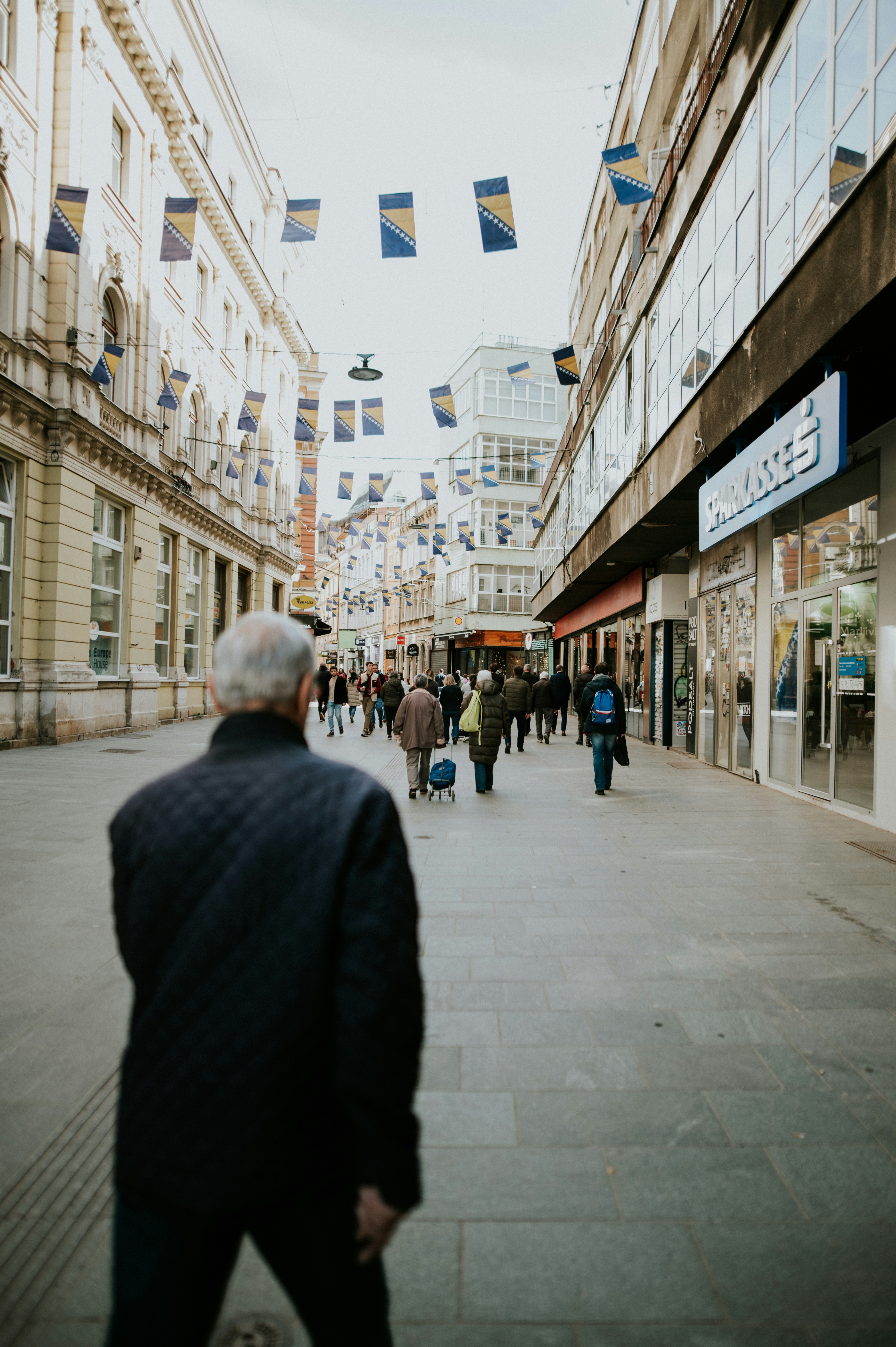 a group of people walking down a street next to tall buildings