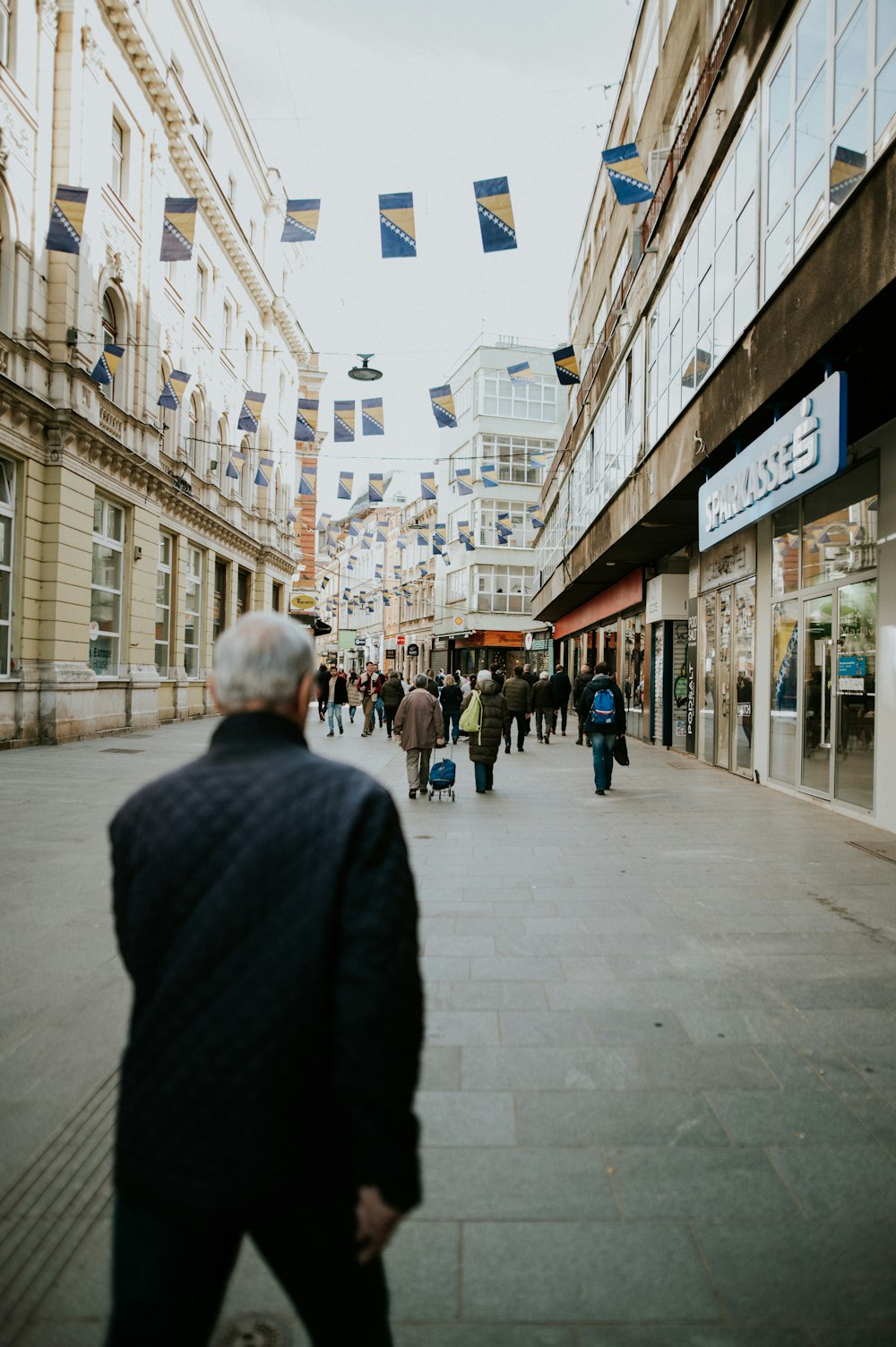 a group of people walking down a street next to tall buildings