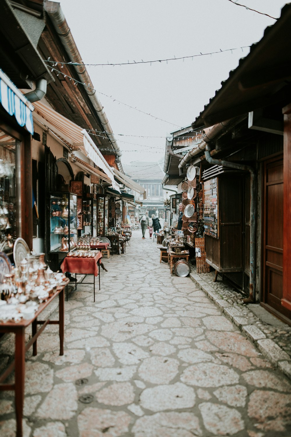 a cobblestone street lined with shops and people