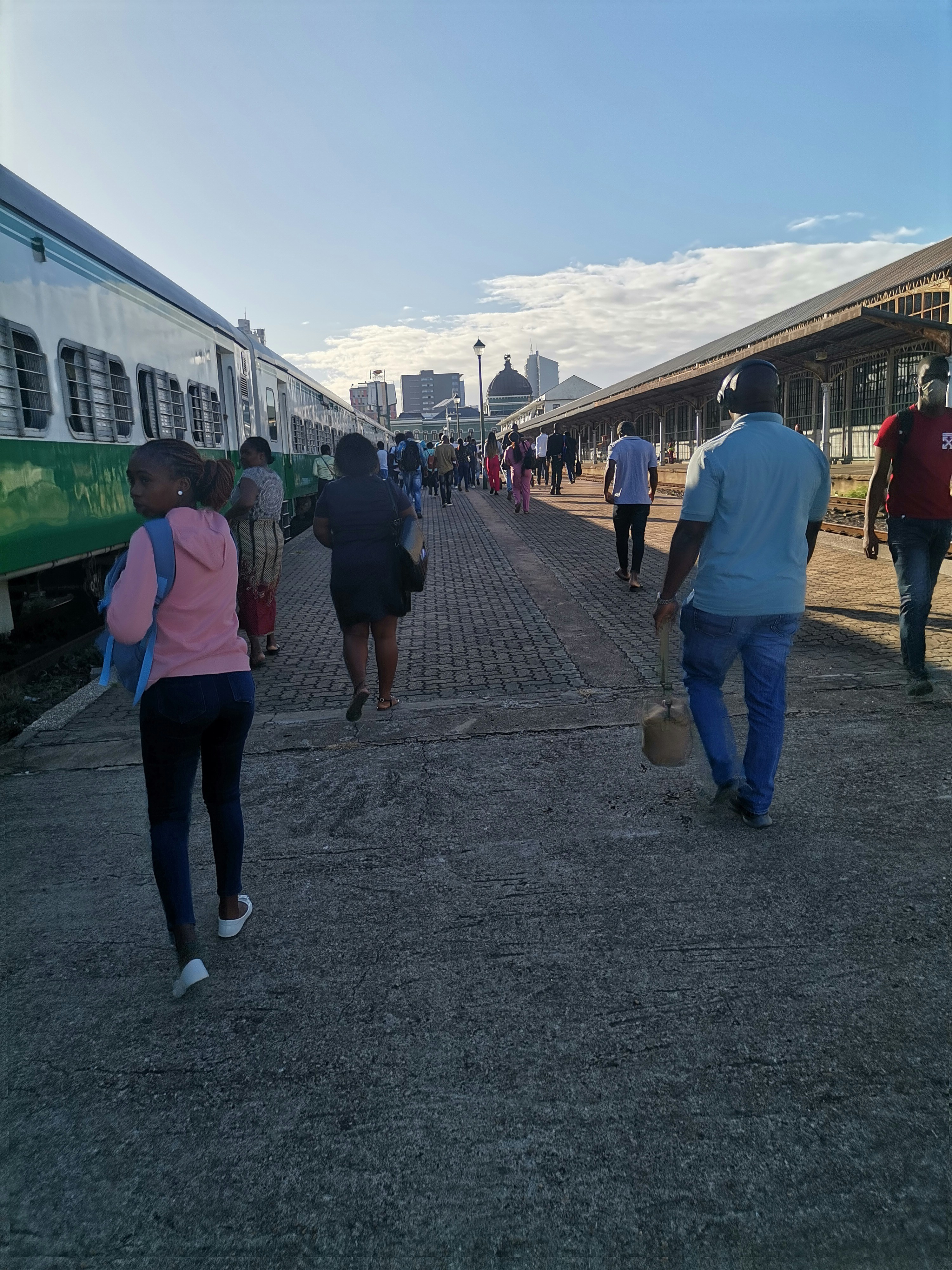 a group of people walking down a sidewalk next to a train
