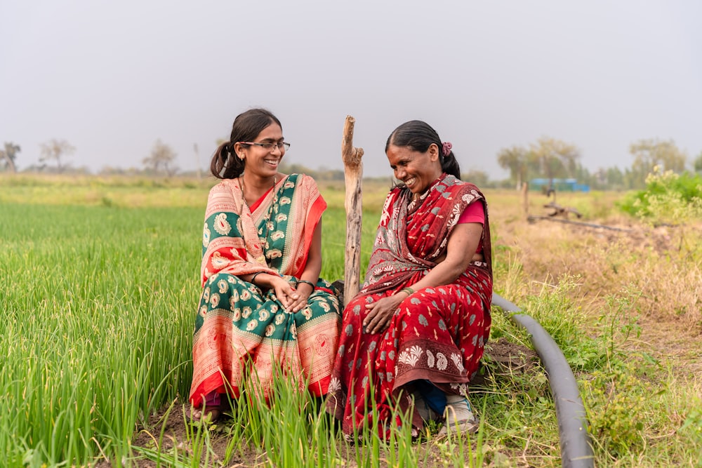 two women sitting in a field with a hose