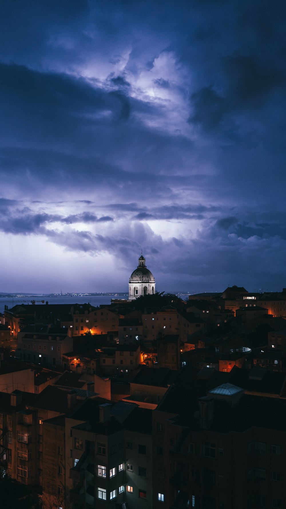 Una vista de una ciudad por la noche con una torre de reloj en la distancia