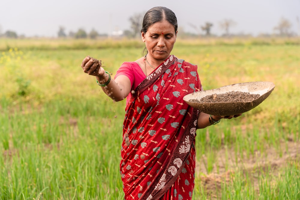 a woman in a red sari holding a bowl