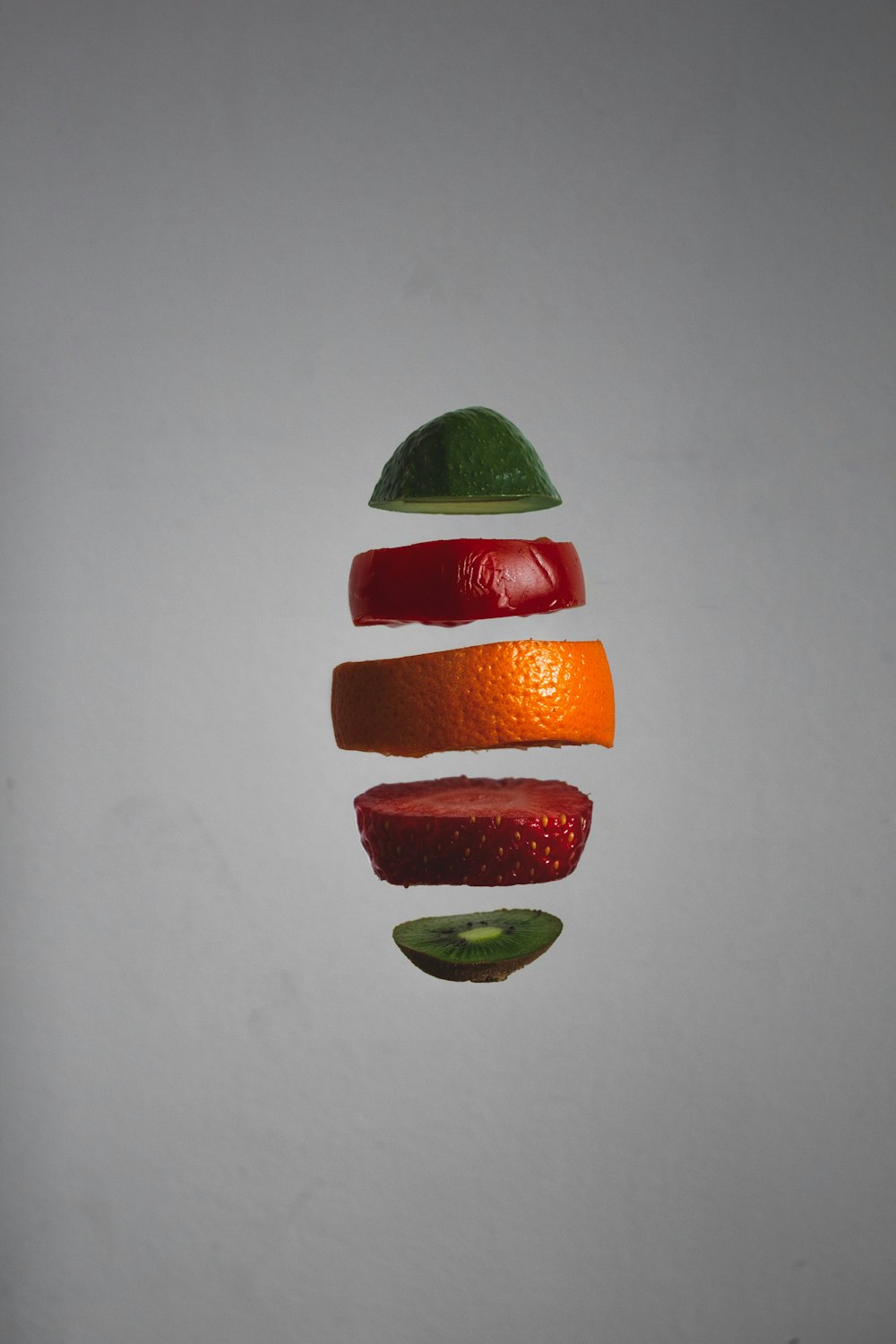 an orange, apple, and kiwi cut in half