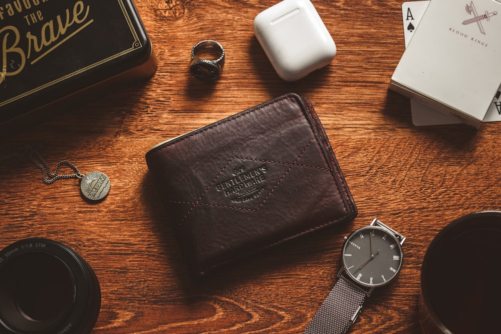 a wooden table topped with a wallet and a watch