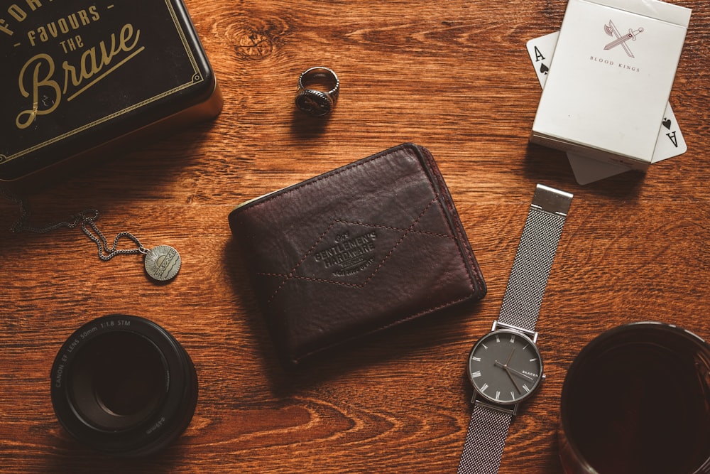 a wooden table topped with a wallet and a watch