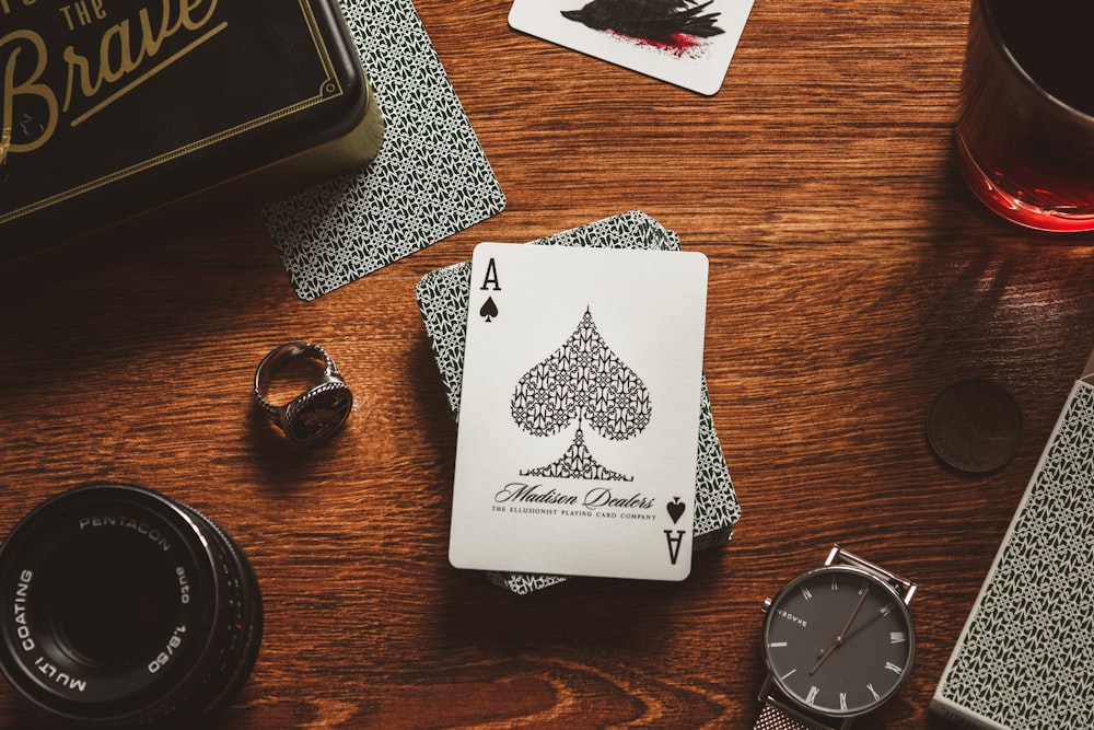 a wooden table topped with playing cards and a watch