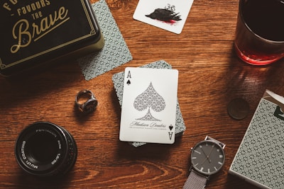 a wooden table topped with playing cards and a watch