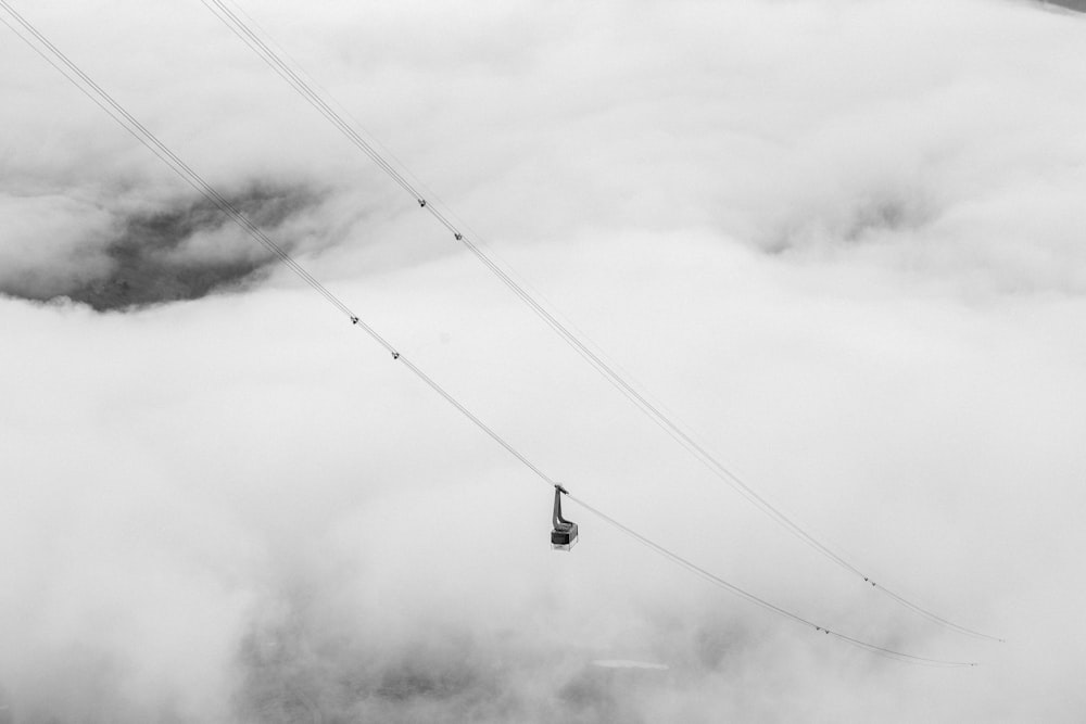 a black and white photo of a ski lift in the clouds