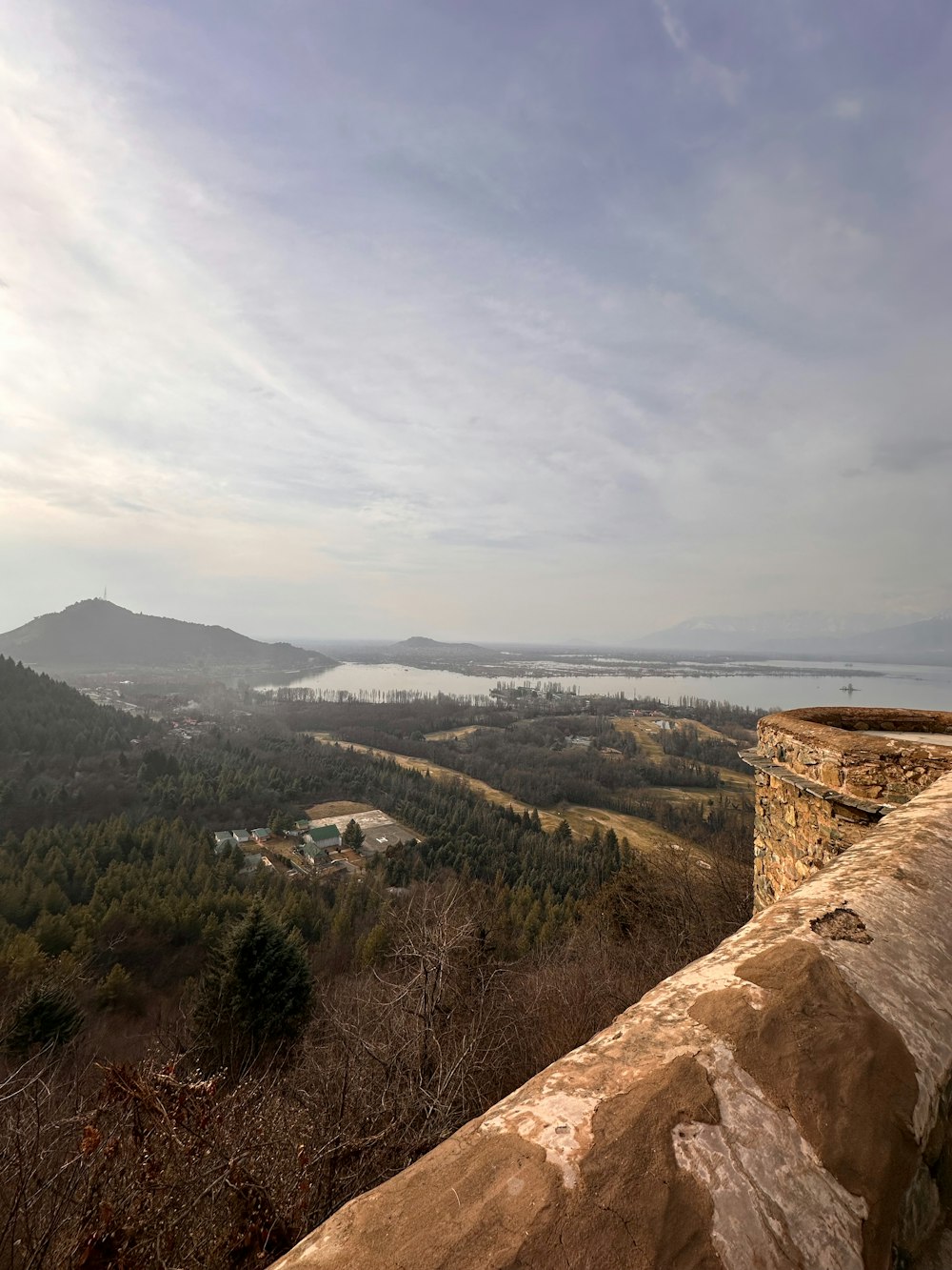 a view of a lake and mountains from the top of a hill