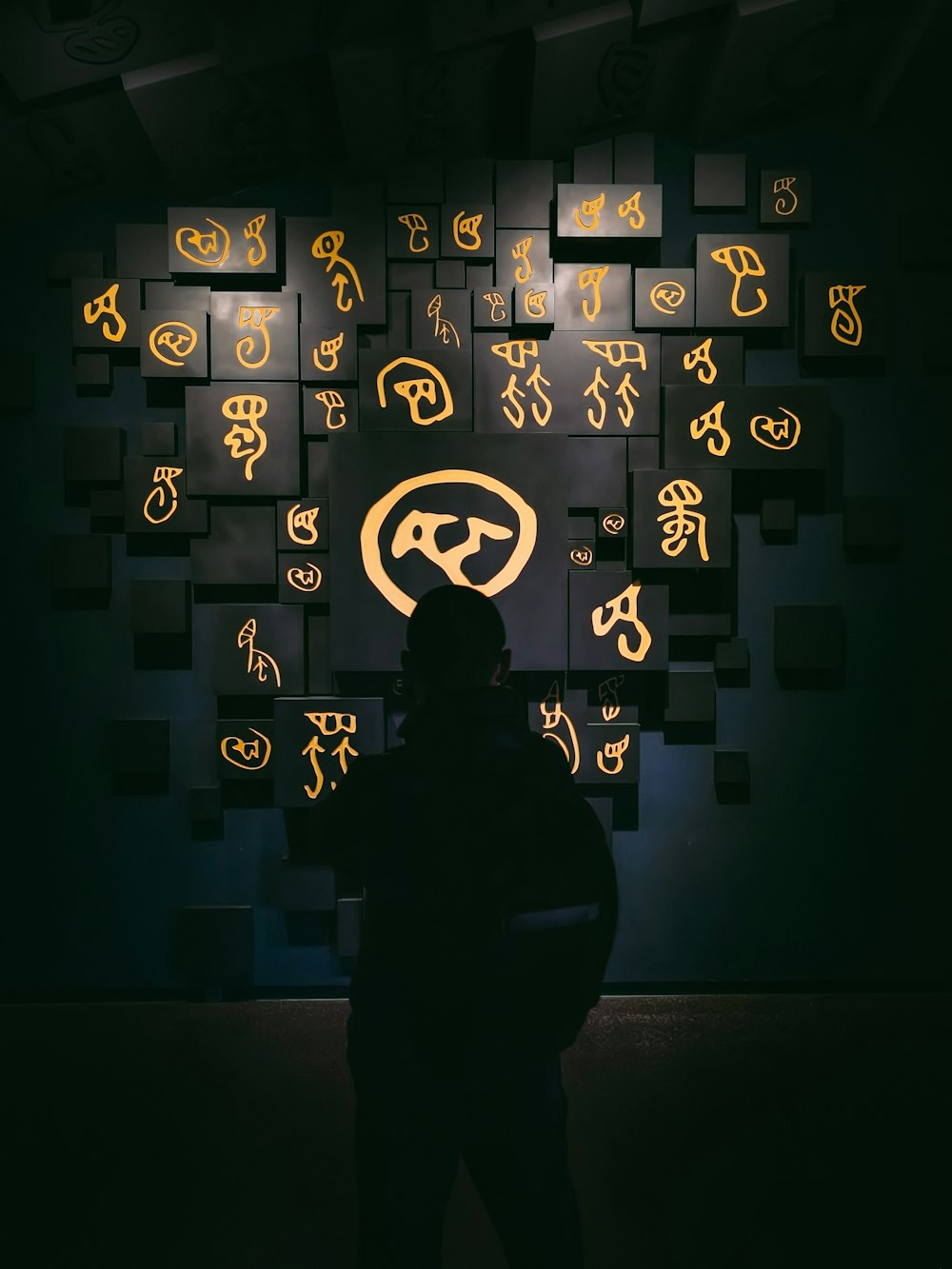 a person standing in front of a wall with a number of symbols on it
